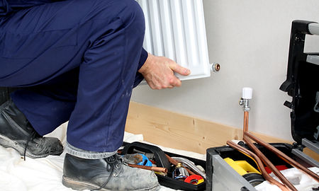 Plumber removing/refitting a central heating radiator
