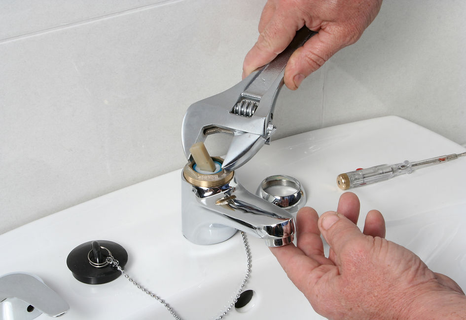 Plumber using an adjustable spanner to fix a chrome bathroom tap fixture