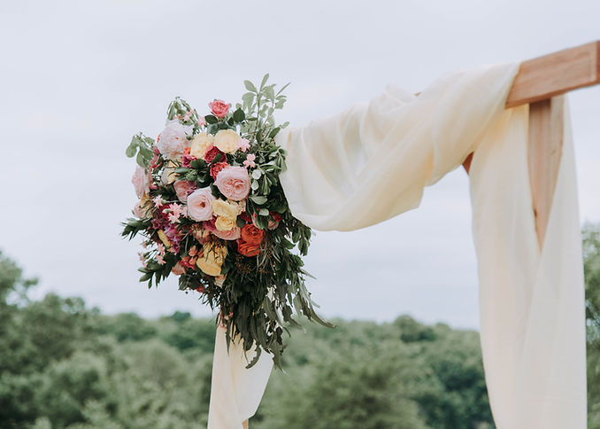 Scenic outdoor wedding venue with wooden arch and covered with a soft white fabric