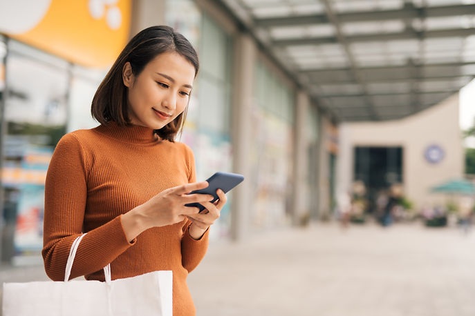 Asian woman checking her smartphone while shopping