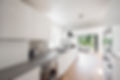 A general view of a modern white handleless fitted kitchen with oak