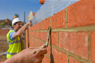 Bricklayers applying mortar to bricks in a wall