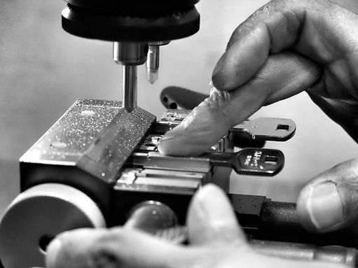 Close-up in black and white of a locksmith's hands working on a metal lock with two inserted keys