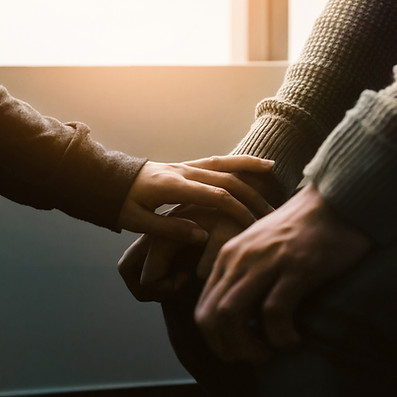 An intimate close-up shot of two hands gently clasping across a table in a comforting manner