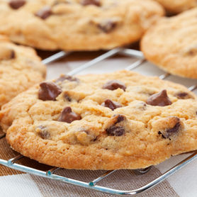 Freshly baked chocolate chip cookies cooling on a wire rack, showcasing their golden-brown color and generous chunks of chocolate.
