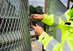 Subway area, man opening the locked wire fence, removing lock and chain