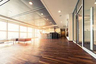 Office hallway with polished wooden floors, large windows streaming sunlight