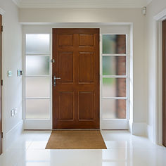 A front door of a new house with a large oak panelled front door