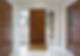 Wooden front door with frosted glass side panels in a modern, bright hallway