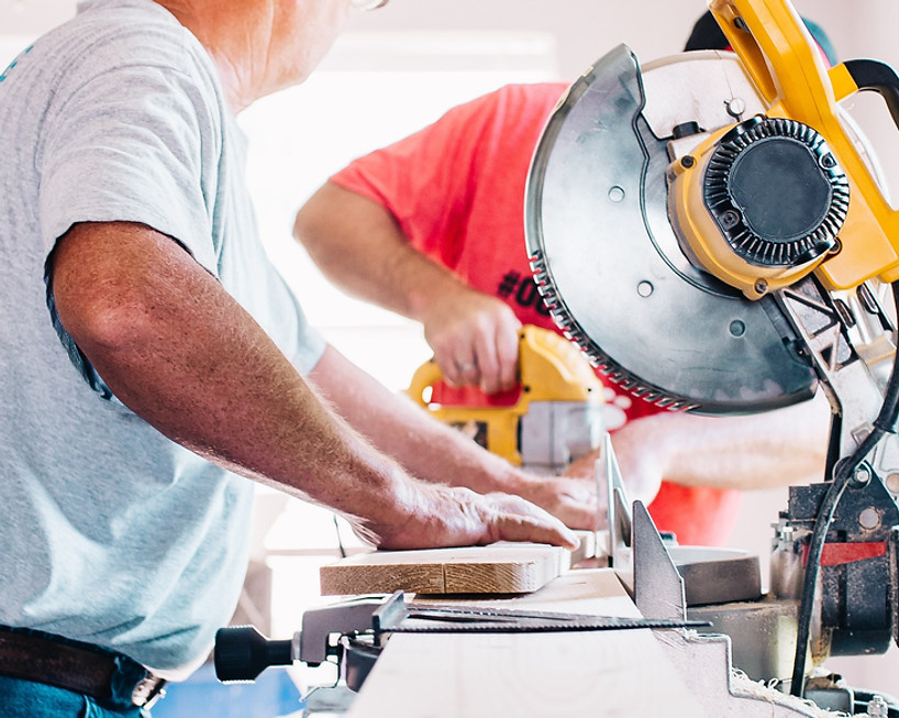 Man cutting wood with a miter saw for property maintenance.