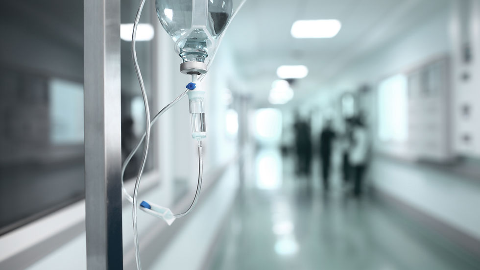 IV drip in focus in a hospital corridor, with blurred figures in the background. Bright, sterile setting with a teal and white color scheme.