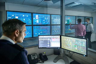 A control room with multiple large screens displaying complex data