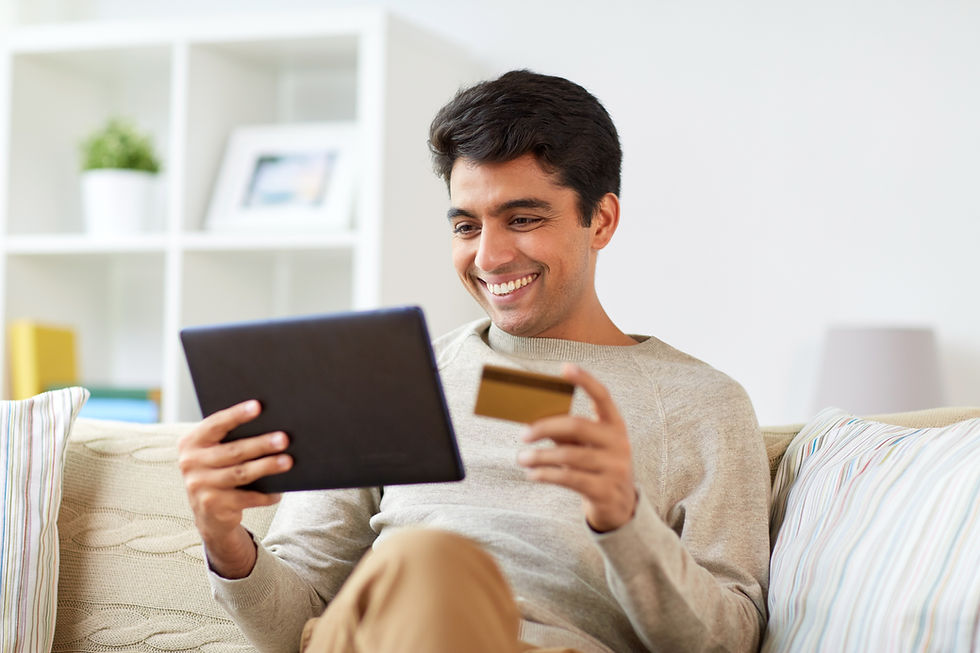 A man looks at his ipad and credit card while smiling.