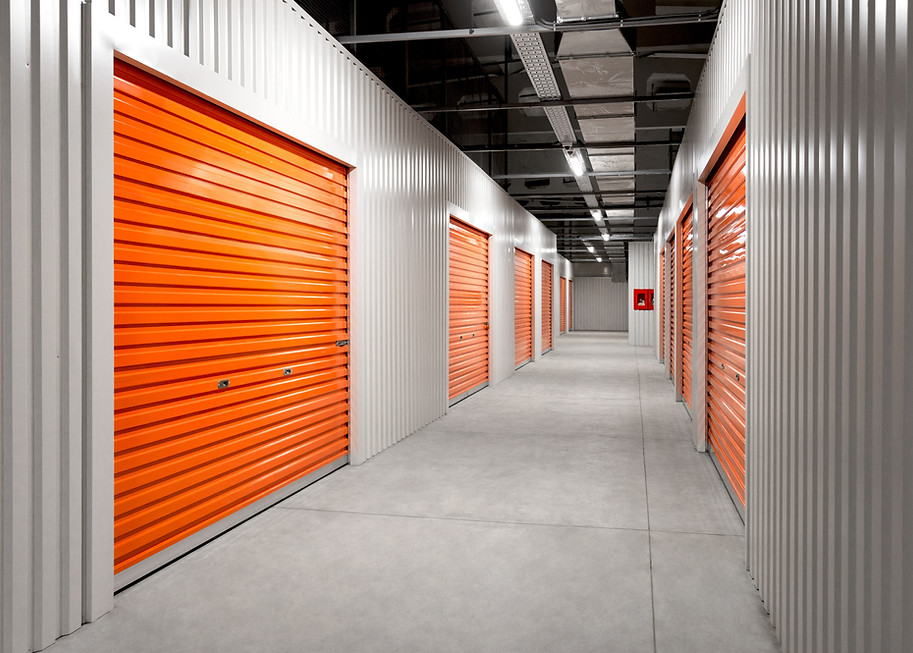 Clean, well-lit corridor of a secure climate-controlled storage facility with orange roll-up doors