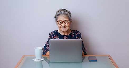 Uma senhora idosa interagindo com um computador, sorrindo