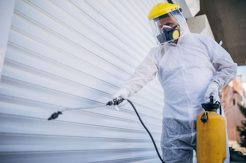Industrial painter wearing a protective mask and suit applying white coating to a curved metal panel