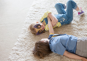 Boy and girl messing about on rug in living room