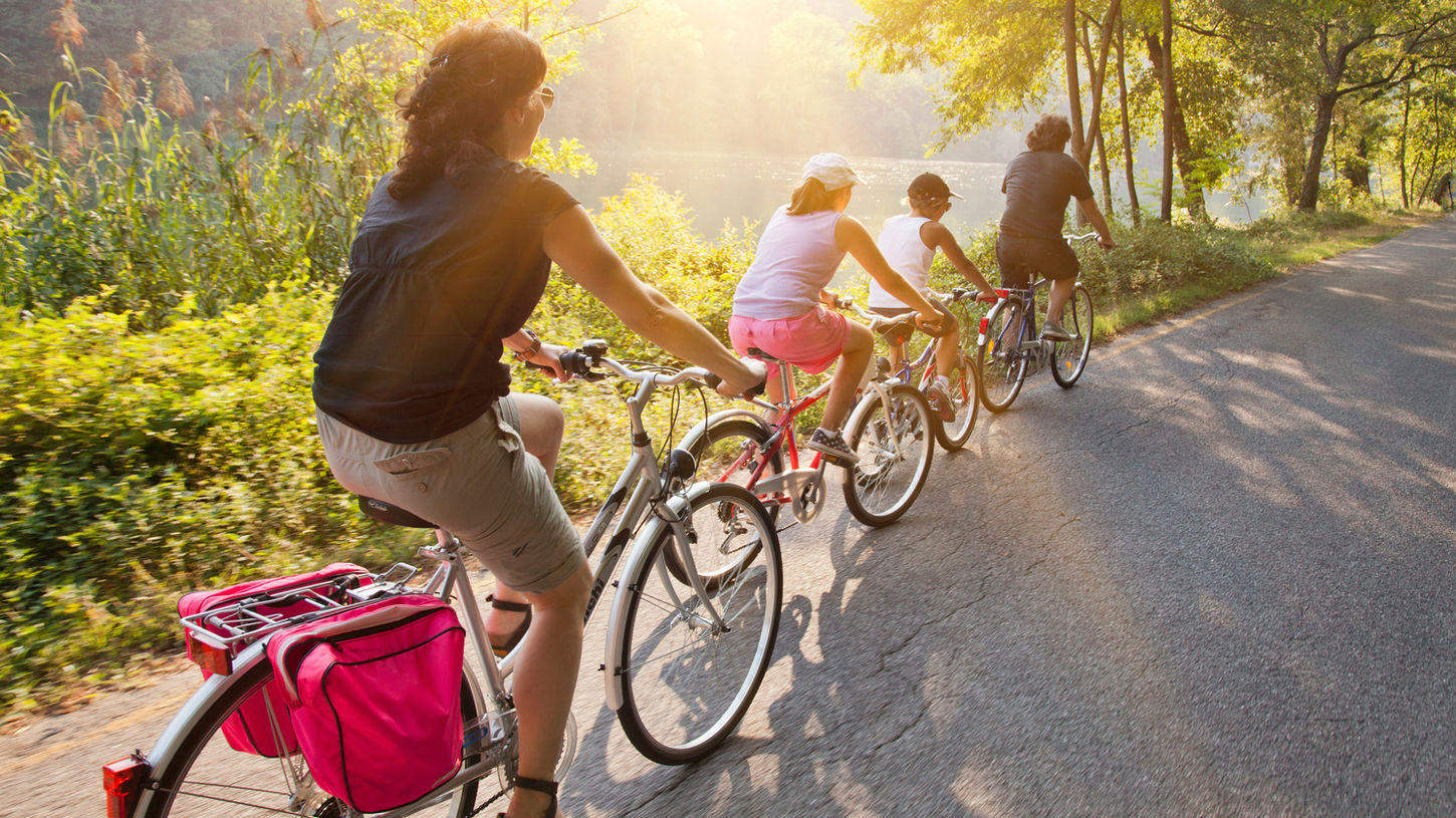 Groupe d'amis à vélo sur une voie verte au bord de l'eau, lumière du soir