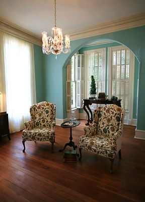 Bright sitting room with teal walls and two floral patterned wingback chairs