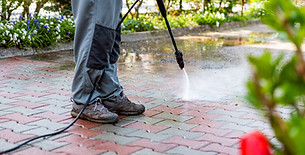 Close up of a pressure washer spray nozzle cleaning dark dirt off a paving stone patio area