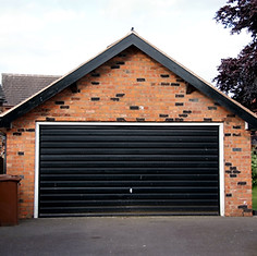 Brick garage with a black roll-up door