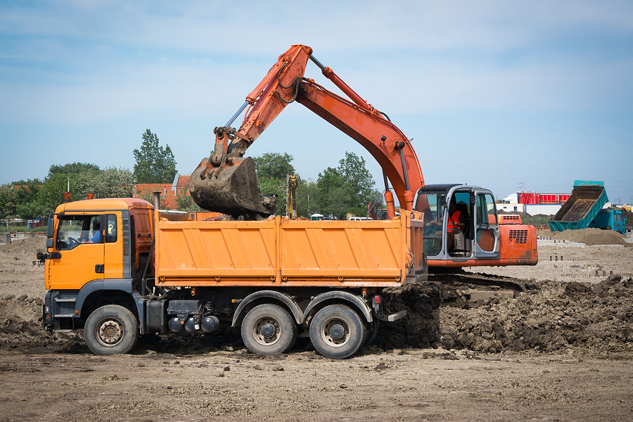 Industrial truck loader excavator moving earth and unloading into a dumper truck
