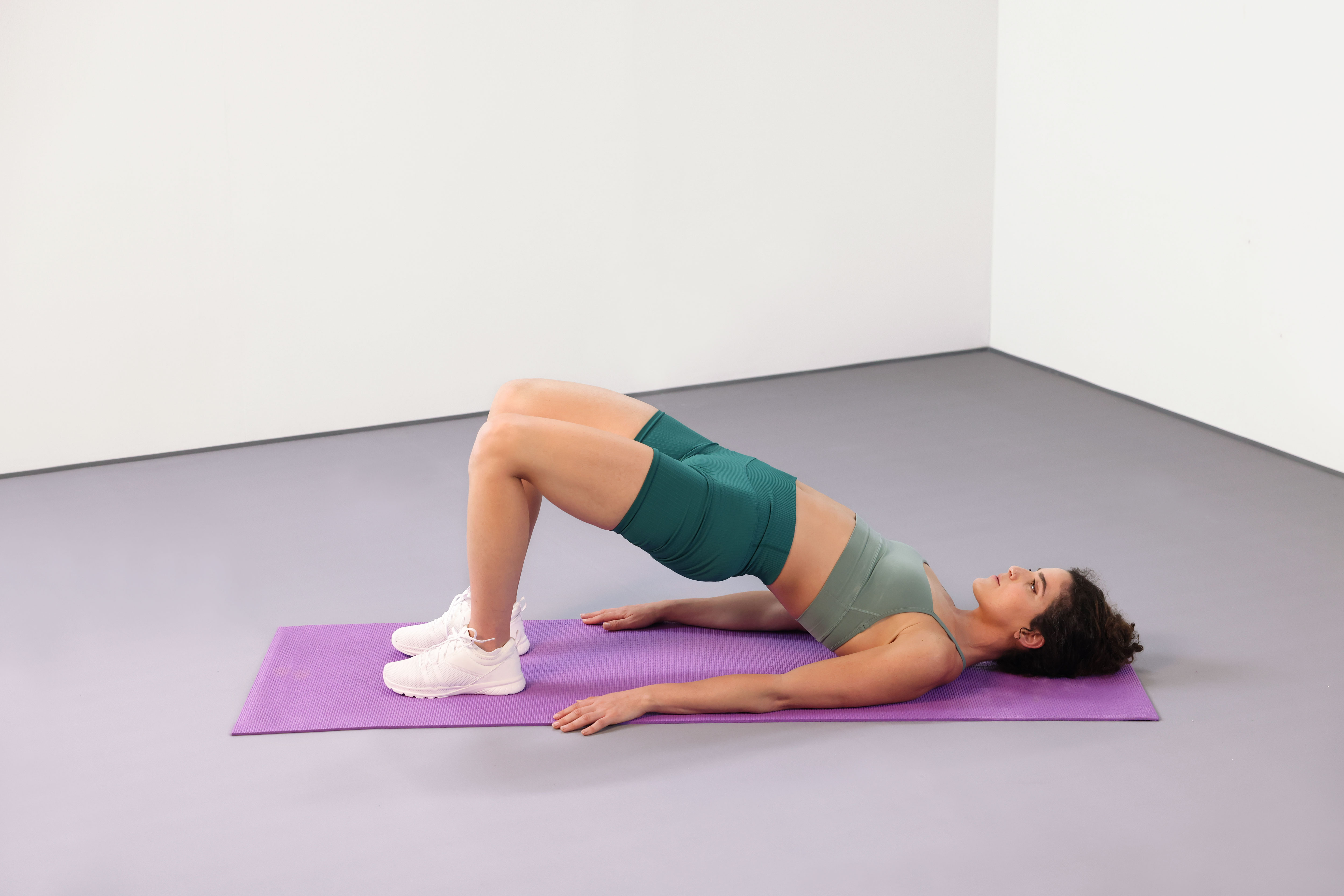 Demonstration of a glute bridge exercise on a mat.