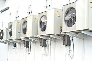 Multiple outdoor HVAC condenser units mounted on a building wall