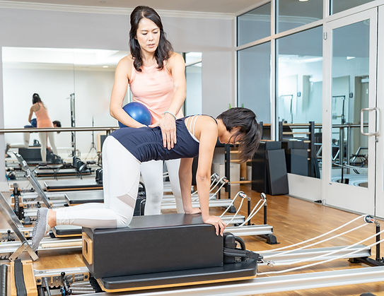 Woman participating in clinical Pilates being guided by Pilates instructor