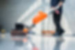 A person operates an orange floor polishing machine on a shiny surface