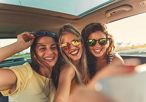 Three diverse women smiling together in a car