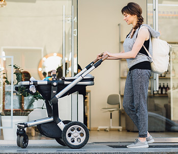 A mother pushes a stroller with her sleeping newborn down the streets of Los Angeles