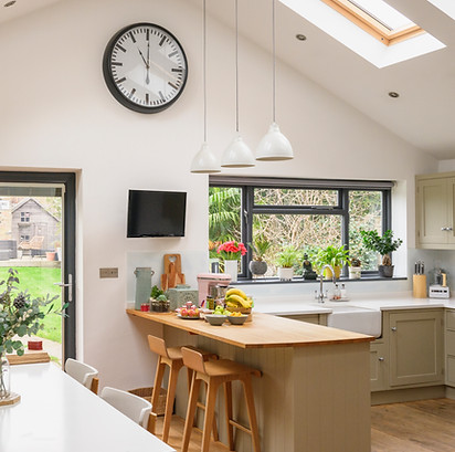 Unoccupied kitchen, dining table seating six, brick wall, hardwood floor, wall clock