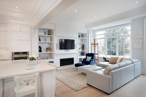 Spacious white open-plan lounge with plush corner sofa, fireplace and modern kitchen area