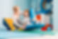A woman smiles supportively at a child sitting on a blue swing