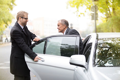 Chauffeur opening car door for businessman