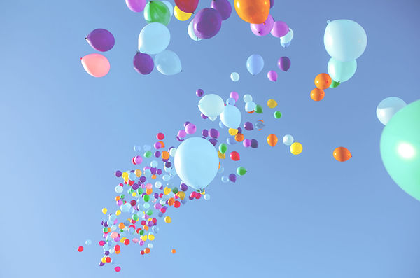 Bunte Luftballons steigen in den blauen Himmel