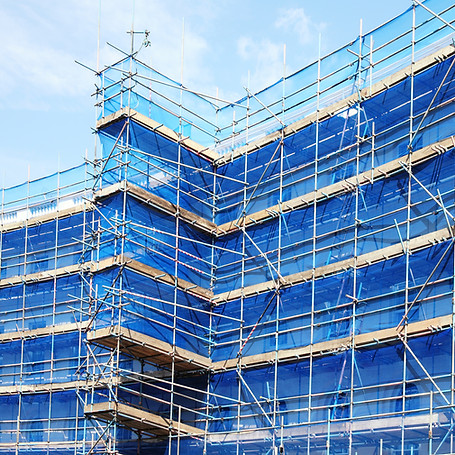 A building with a grid of metal scaffolding and blue safety netting