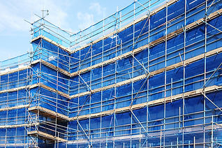 A building with a grid of metal scaffolding and blue safety netting