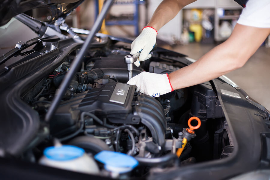 Mechanic using a wrench to work on a car engine, wearing white gloves