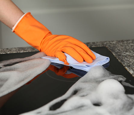 Hand in protective glove cleaning a stove