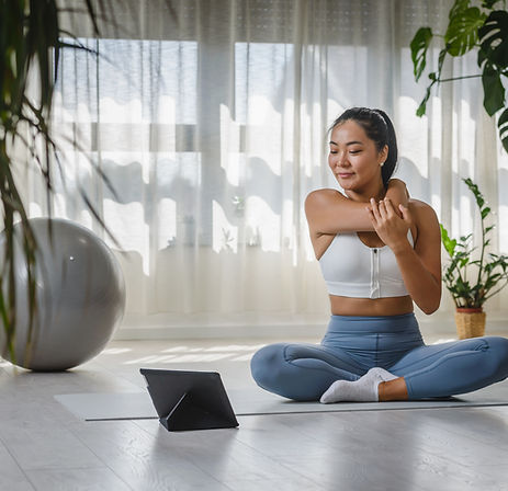 Smiling Asian woman watching yoga instruction using a tablet
