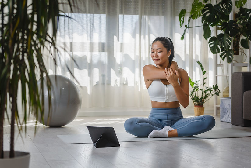 Smiling Asian woman watching yoga instruction using a tablet