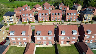 Aerial view of a suburban neighborhood with rows of red-brick houses featuring gabled roofs