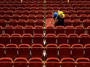 Cleaner in uniform wipes seats in an empty theatre hall — how to run a cleaning business
