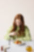 An image of a red-haired girl in a green shirt looking down at the fork she is holding in her hand
