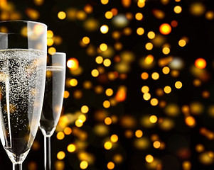 Three Champagne glasses with wine and sparklings, against yellow and orange lights in the