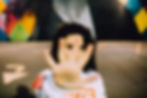 A girl artistically poses with her hand outstretched towards the camera, set against a vibrant mural backdrop.