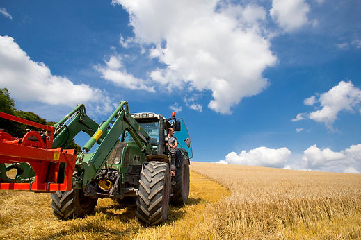 Tractor arranging straw bales in sunny rural field