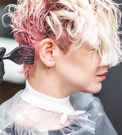 Woman with short blonde hair in the process of getting her hair dyed pink by a professional hair stylist
